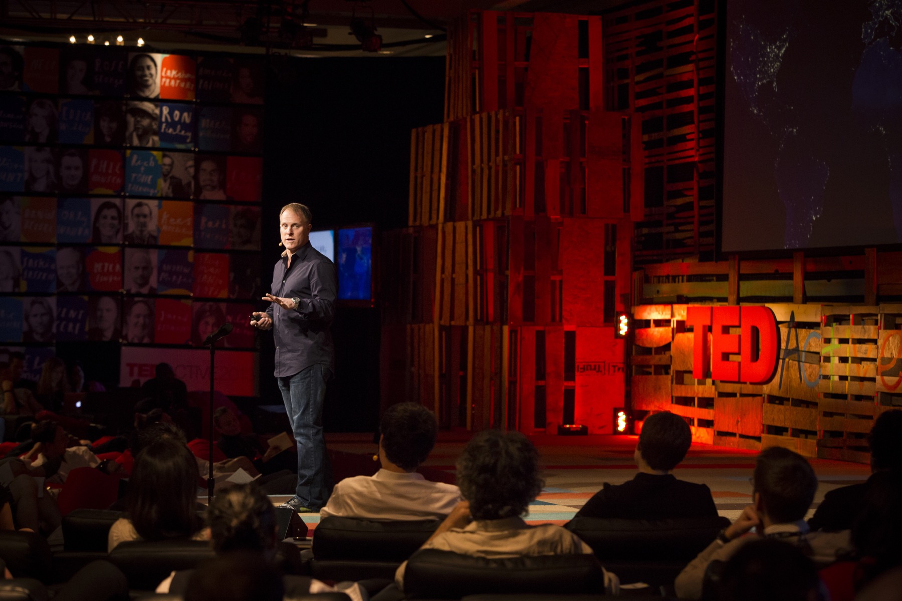 John Bates speaking onstage at TEDActive 2013 with the TEDActive logo behind him.